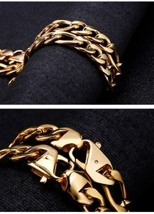 Macro detail of gold-tone stainless steel NK link bracelet with lobster clasp on dark fabric
