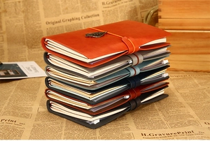 Close-up of vintage leather traveler notebooks with elastic straps and bronze leaf charms