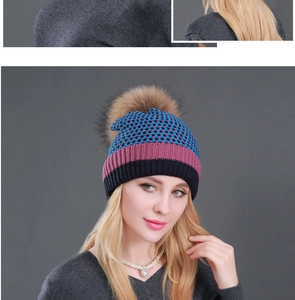 Detail of a plaid knit beanie with a fluffy brown pom pom and black ribbed cuff for winter
