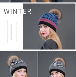 Detail view of stylish winter knitted beanie featuring a large faux fur pom-pom decoration