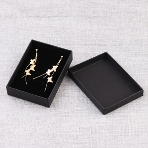 Golden butterfly tassel earrings presented in a minimalist black kraft paper jewelry box