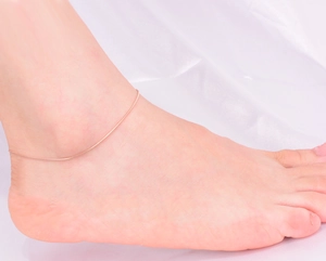Close-up of minimalist rose gold snake chain anklet with long bar on model's ankle