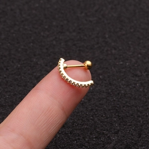 Detail shot of a gold-plated stainless steel curved barbell stud with a clear zircon stone