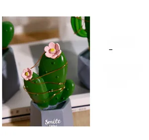 Nahaufnahme eines Kaktus-Dekos aus Harz mit LED-Lichterkette und Smile-Topf für den Tisch