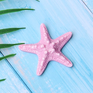 Close-up of pink resin starfish with textured surface on a blue wooden background