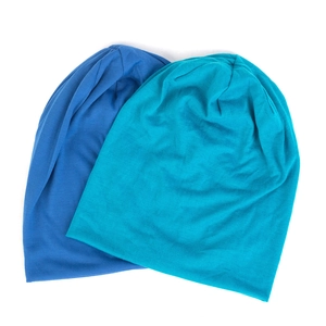 Detail of royal blue and teal double-layered thin knit beanies on white background