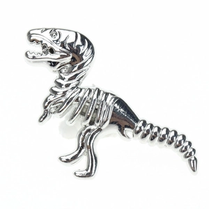 Macro detail of the silver Tyrannosaurus Rex skeleton brooch with polished metal finish