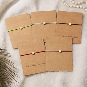 Close-up of five colorful braided wish bracelets with gold beads on display cards