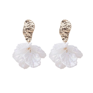 Detailed view of white petal earrings with pearls and hammered gold textures