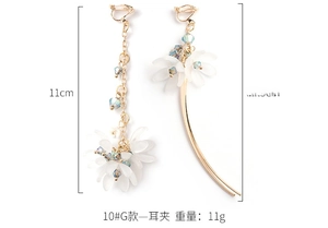 Détail des boucles d'oreilles clips asymétriques avec pétales de coquillage et cristaux bleus