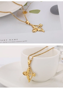 Détail macro du collier flèche de Cupidon doré avec cœurs sur une tasse à café blanche