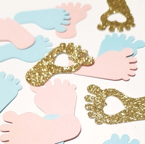 Flat lay of pink, blue, and gold glitter baby foot confetti for gender reveal parties
