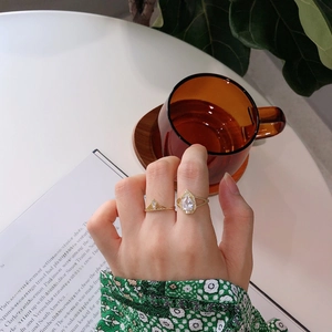 Close-up of model wearing two gold plated rings with pear shaped zircon and crown band