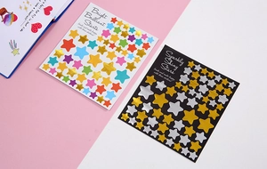 Close-up of colorful gold foil star stickers on white and black sheets for scrapbooking