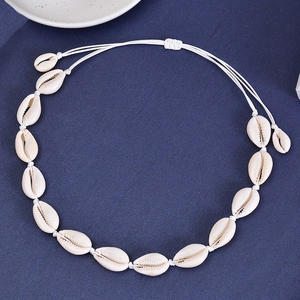 Detail of handmade bohemian necklace featuring natural white seashells and woven cotton cord