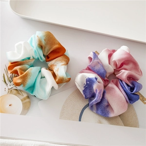 Detail of colorful tie-dye satin scrunchies in teal and purple on a stylish magazine