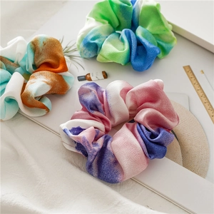 Macro detail of tie-dye silk scrunchies in green, orange, and purple color gradients