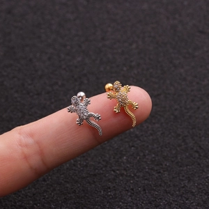 Macro detail of silver and gold gecko stud earrings with sparkling cubic zirconia stones
