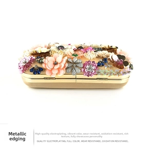 Detail of beaded evening bag featuring colorful floral gemstone clusters and metal edging