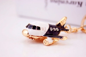 Detail of metal airplane keychain with navy blue enamel wings and inlaid rhinestones