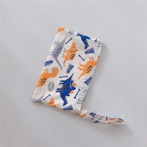 Detail of white cotton fabric pouch with colorful dinosaur patterns and portable wrist strap