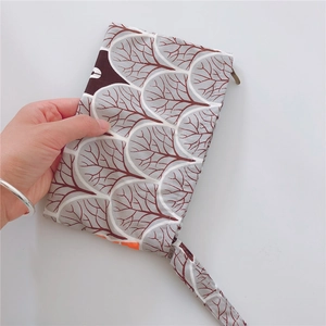 Detail of portable cotton zipper pouch with leaf pattern and hand strap for small items