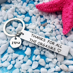 Macro shot of stainless steel keychain with funny humor engraving on sand background
