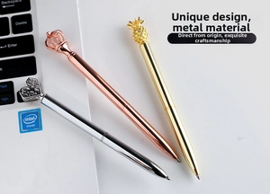 Detailed view of metal pens with crown, pineapple and heart shapes on a desk