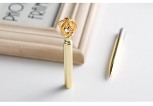 Macro shot of gold metal ballpoint pen featuring a crystal crown top design