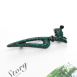 Sparkling green crystal fox head brooch with black eyes on a polished metal base