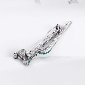 Silver stylized Eiffel Tower brooch with green gemstones showing the back pin mechanism