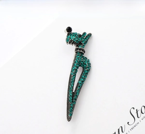 Macro shot of green rhinestone puppy brooch with black crystal eyes in silver finish