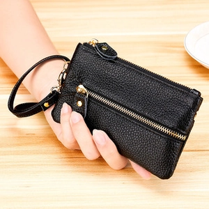 Close-up of black genuine leather wallet with lychee texture and wrist strap held by hand