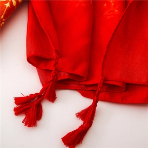 Detail of red sun protection shawl with golden embroidery and woven fringe tassels