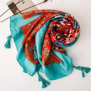 Detail of teal ethnic scarf with orange floral patterns and elegant fringe tassels
