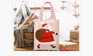 Close-up of burlap Christmas gift bag with Santa Claus 3D embroidery and striped handle