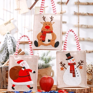 Detailed view of linen Christmas gift bags featuring reindeer, Santa, and snowman designs