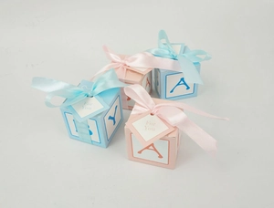 Detail of pink and blue DIY candy boxes with satin ribbons and For You tags for baby showers