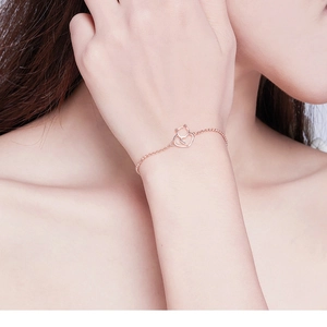Dettaglio del ciondolo a forma di gatto e cuore in oro rosa su un bracciale a catena