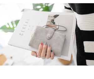 Light gray frosted wallet with wrist strap held by a model in a modern lifestyle setting
