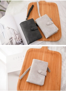 Detail of short tri-fold matte wallets in black and grey with wrist straps and snaps