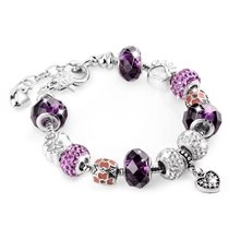 Macro view of purple and silver beaded snake chain bracelet with sparkling heart pendant
