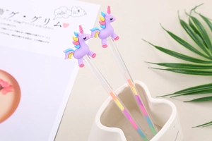 Close-up of cute unicorn pens with purple silicone toppers and rainbow gradient ink barrels