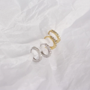 Close-up of gold and silver sterling silver hoop earrings with pave diamonds on white paper