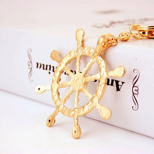 Golden ship wheel keychain with sparkling crystal rhinestones on white book background