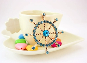 Detailed macro view of a golden ship rudder pendant with sparkling blue crystals