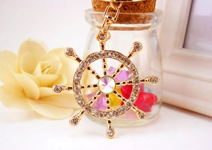 Macro shot of gold ship wheel keychain with sparkling crystals and a colorful centerpiece