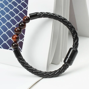 Detail of men's leather braided bracelet with tiger eye beads and black magnetic buckle