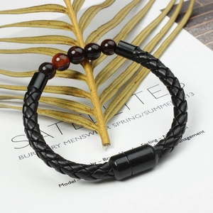 Detail showing the woven black leather texture and dark red stone beads of the bracelet
