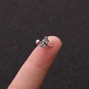 Miniature silver dragonfly stud earring with zircon wings held on a fingertip